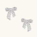 Pair of silver filigree bow-shaped stud earrings with marquise zirconia center stones and star-set crystal accents.
