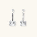 Modern silver dangle earrings with geometric cube pendants and chain design on minimalist background.