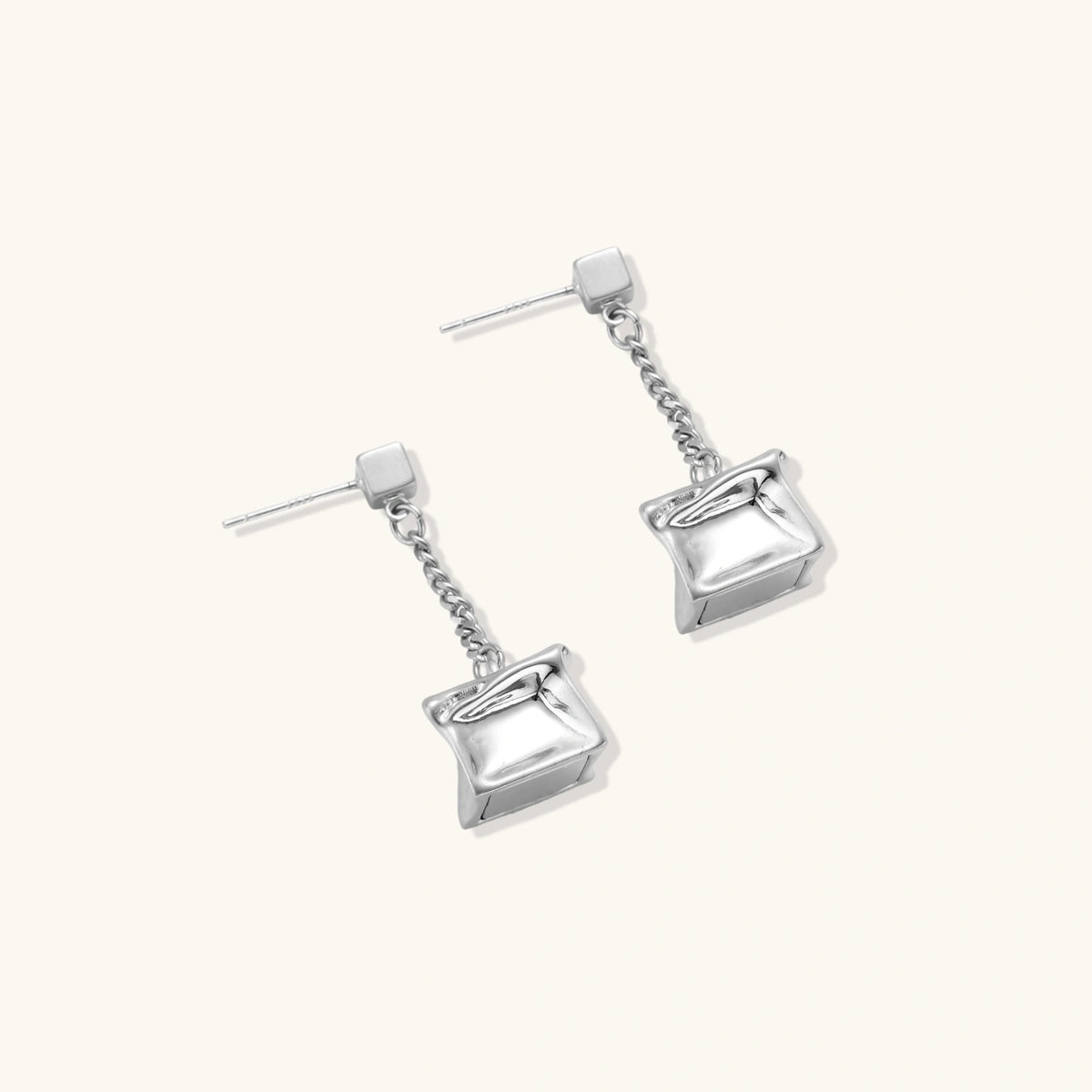 Modern silver dangle earrings with geometric cube pendants and chain design on minimalist background.